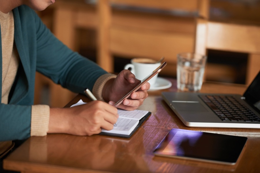 hands-unrecognizable-man-sitting-table-cafe-with-gadgets-writing-notebook